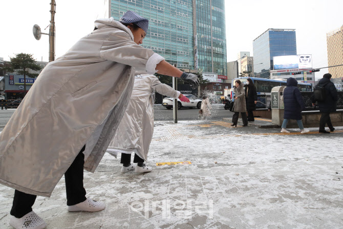 [포토]전날 내린 눈으로 미끄러운 길, 염화칼슘 뿌리는 시민