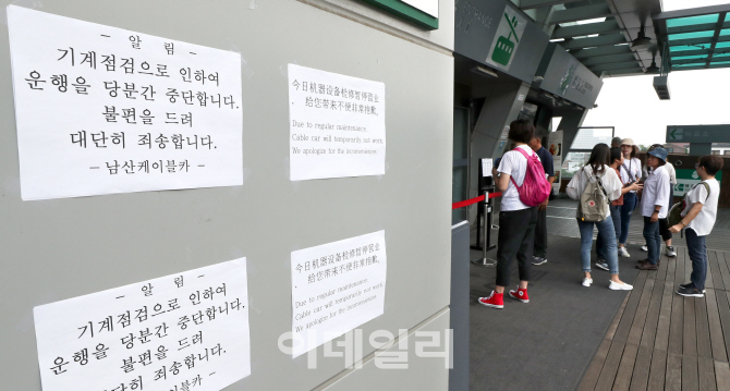 [포토]남산 케이블카 운행중단 안내문 살펴보는 관광객들