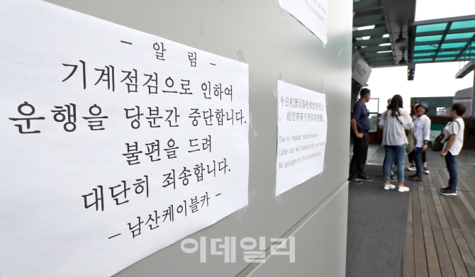 [포토]남산 케이블카 운행중단 안내문 살펴보는 외국인 관광객들