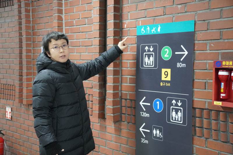 서울 교통약자안내표지 ‘모두의 지하철’ 프로젝트 디자인을 총괄한 홍익대 시각디자인학과 이연준 교수가 시청역 표지 앞에 서 있다. (사진=사단법인 무의)