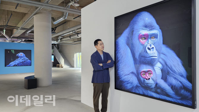 작가 고상우가 사비나미술관 개인전 ‘너와 함께 쉬는 숨’에 내놓은 작품 ‘내가 여기에 있다’(I Am Here, 2026, 150×150㎝) 옆에 섰다. 응급 제왕절개로 태어난 아기 고릴라와 엄마 고릴라가 어렵게 회복한 뒤 ‘너와 함께 숨을 쉬는’ 장면을 만들어냈다(사진=오현주 문화전문기자).