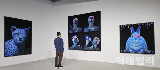 고상우 개인전 ‘너와 함께 쉬는 숨’ 전경. ‘자화상’ 연작 양쪽으로 ‘사라’(Sarah, 2026, 210×150㎝·왼쪽)와 ‘사라진 감각’(Lost Senses, 2026, 150×150㎝)이 보인다. 화장품 임상시험에 나섰다가 한쪽 눈의 시력을 잃은 토끼는 알록달록한 ‘마스카라 창살’ 안에 갇혀 있다(사진=오현주 문화전문기자).