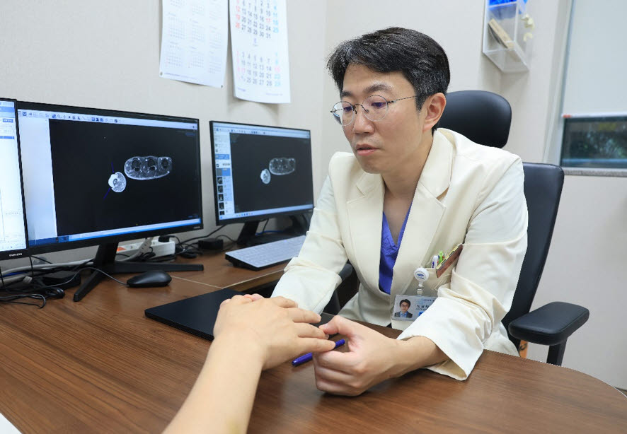 이경태 삼성서울병원 성형외과 교수가 흑색종 환자의 손을 살펴보고 있다.