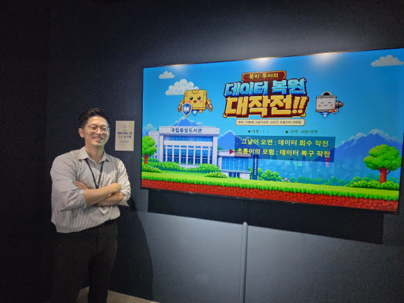 이연수 학예연구사가 AI 프로그램 등을 이용해 복원한 게임 앞에서 기념촬영을 하고 있다(사진=이윤정 기자).