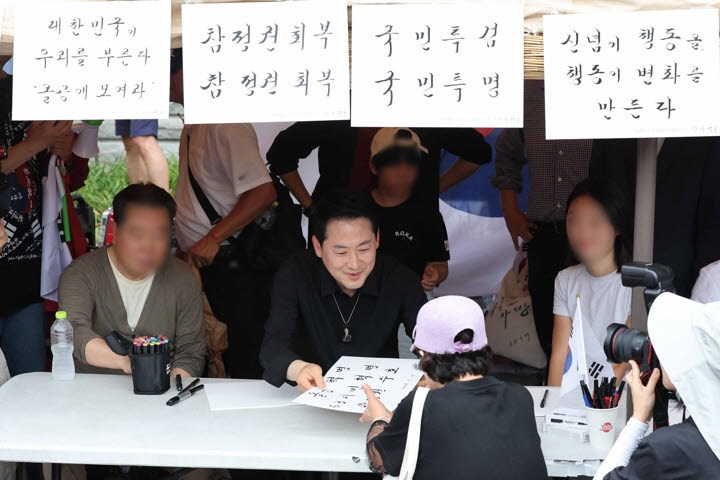 6·3지방선거 투표용지 부족 사태로 촉발된 잠실 개표소 봉쇄 시위가 이어진 17일 국민의힘 장동혁 대표가 서울 송파구 올림픽공원 핸드볼경기장 앞에서 집회 참가자들에게 붓글씨를 선물하고 있다.(사진= 연합뉴스)