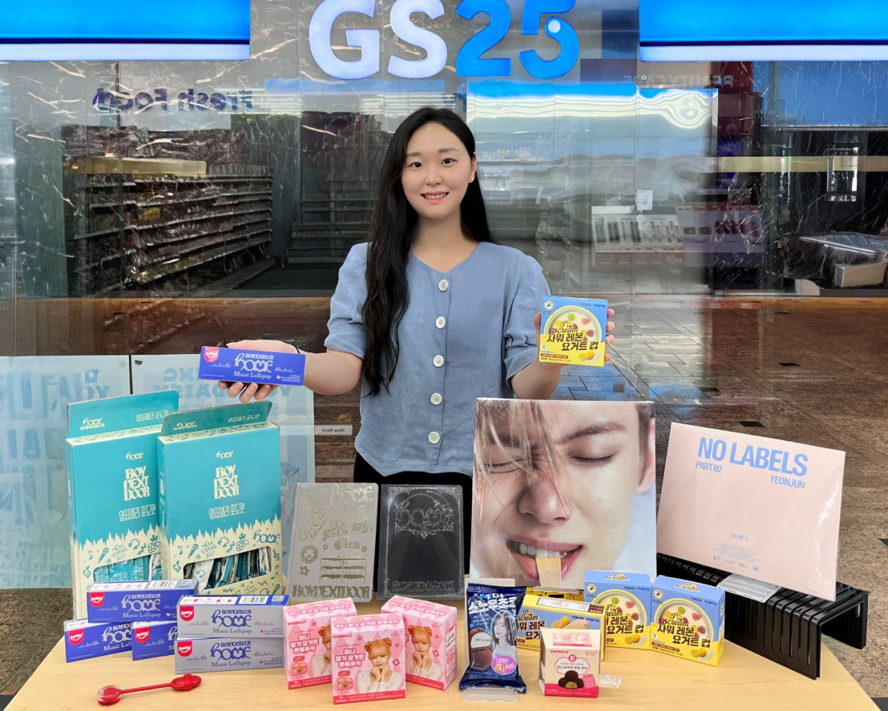 GS25에서 모델이 K팝 아이돌 협업 상품 앞에서 포즈를 취하고 있다 (사진=GS25)