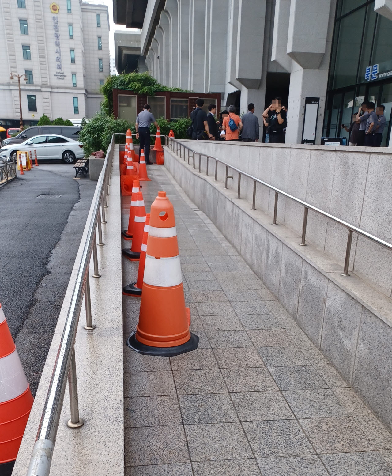 22일 낮 12시30분께 인천시청 북문 앞 진출입 경사로에 고깔 십여개가 놓여 있어 장애인들이 청원경찰관에게 항의하고 있다. (사진 = 이종일 기자)