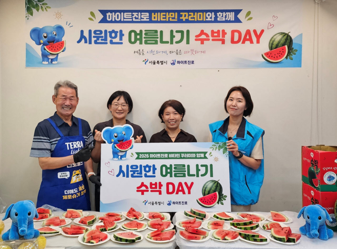 지난 22일 서울역 쪽방촌에서 2026 하이트진로 비타민 꾸러미와 함께 시원한 여름나기 ‘수박 DAY' 행사가 열렸다. (왼쪽부터) 쪽방촌 주민, 서울시 이신옥 팀장, 서울역 쪽방상담소 유호연 소장, 하이트진로 관계자가 기념 촬영을 하고 있다.