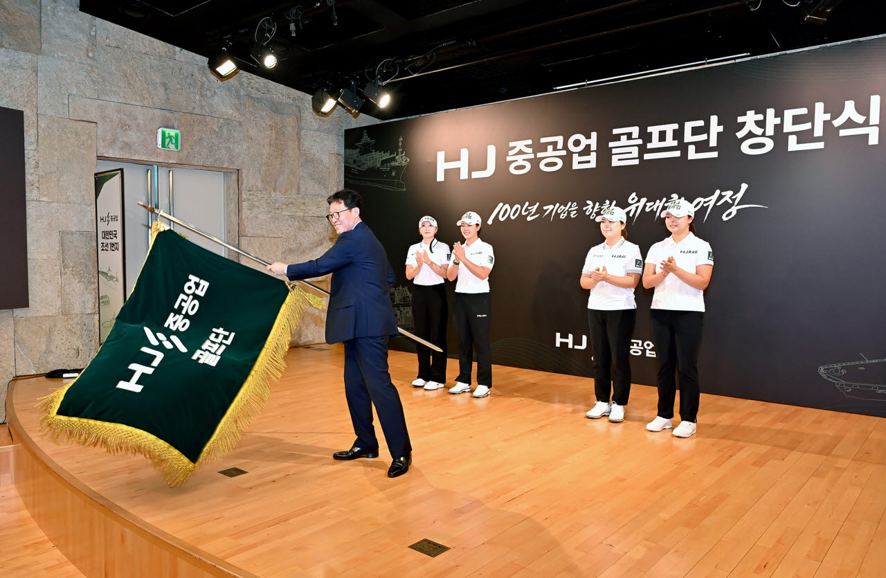 HJ중공업이 24일 서울 용산구 HJ중공업 남영 사옥에서 박지영 등 5명으로 구성된 HJ중공업 골프단 창단식을 개최했다고 밝혔다. 사진은 송경한 HJ중공업 대표이사 사장이 깃발 퍼포먼스를 하는 모습.(사진=HJ중공업 제공/연합뉴스)
