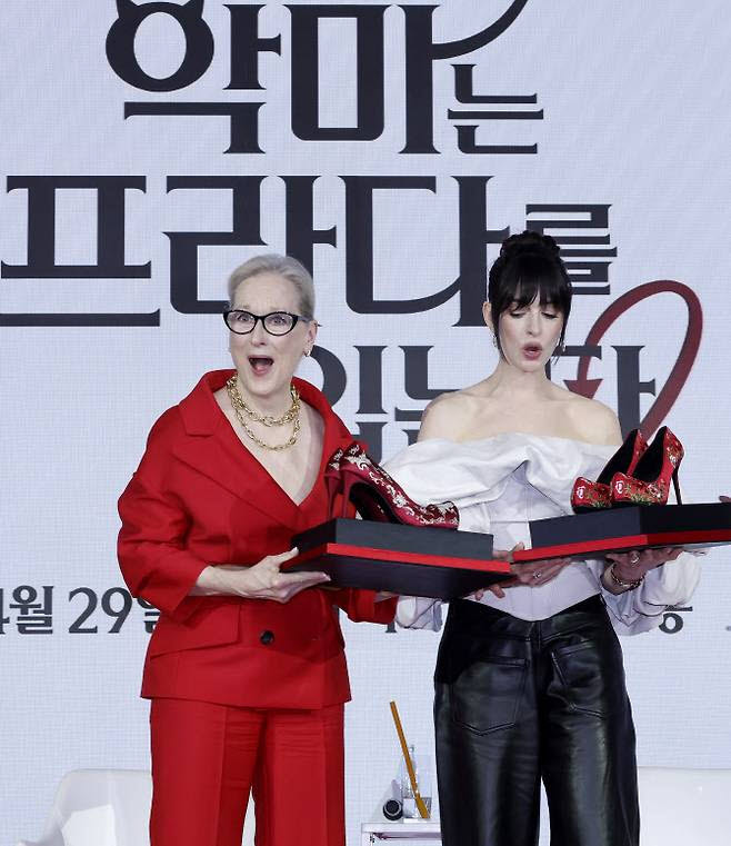 배우 메릴 스트립(왼쪽), 앤 해서웨이가 ‘악마는 프라다를 입는다2’ 내한 기자간담회에서 관계자에게 꽃신 선물을 받은 뒤 깜짝 놀라고 있다.(사진=뉴시스)