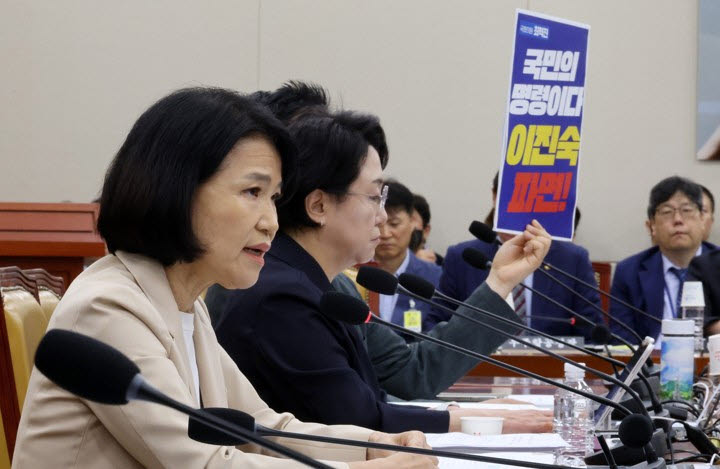 지난 19일 열린 과학기술정보방송통신위원회 전체회의에서 이진숙 국민의힘 의원이 발언을 하는 도중 무소속 최혁진 의원이 뒤편에서 파면 촉구 손팻말을 들어 항의하고 있다. (사진=연합뉴스)