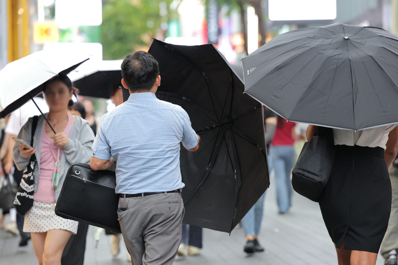 서울 명동 거리를 지나는 한 시민이 비가 내리자 우산을 펼치고 있다. (사진=연합뉴스)