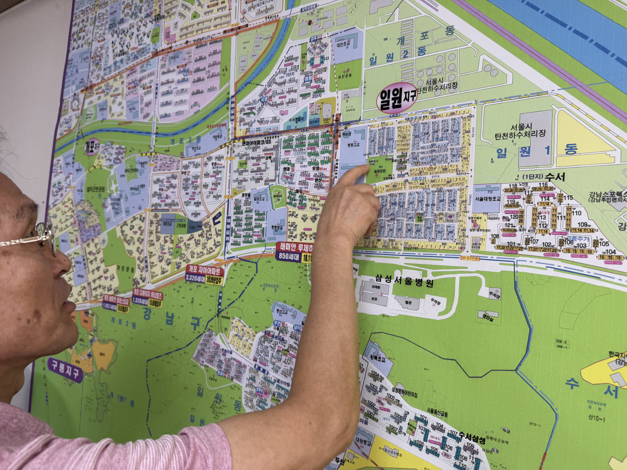 일원동 공인중개사사무소 관계자가 탄천물재생센터가 있는 일원동 일대를 손가락으로 가르키고 있다.(사진=이정현 기자)