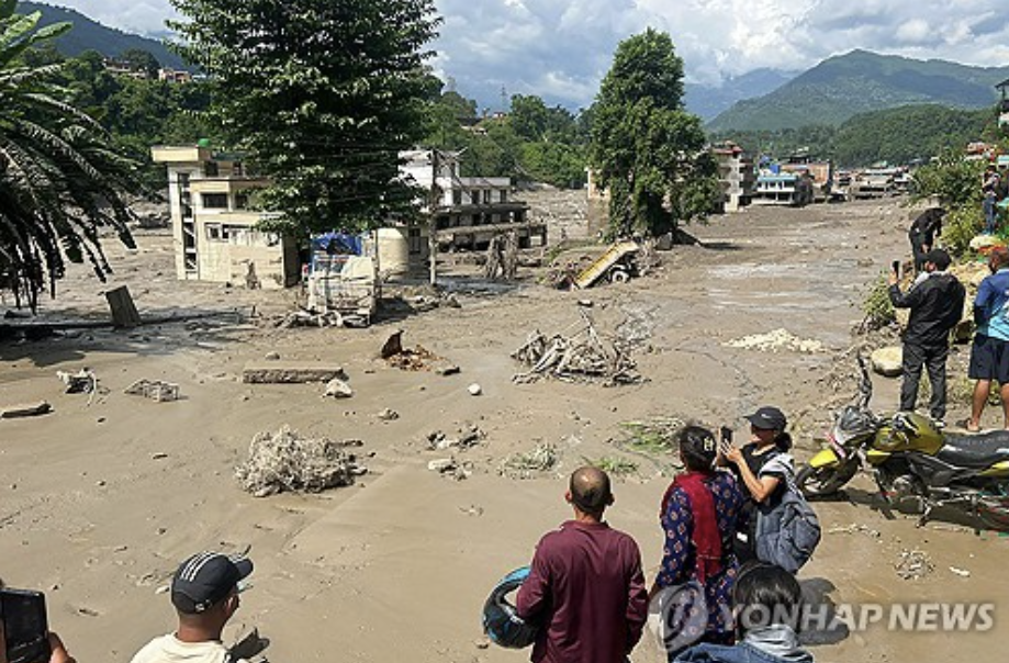 네팔에 발생한 홍수로 진흙탕 물에 잠긴 집들을 바라보고 있는 현지 주민들.(사진=AFP 연합뉴스)