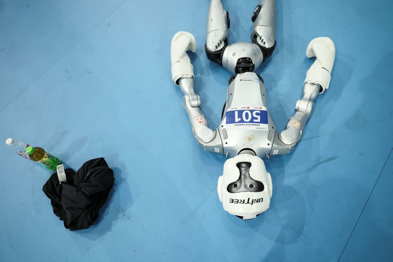 wlsks 23dlf 23일 중국 베이징 국립 스피드스케이팅 경기장에서 열린 ‘2026 세계 휴머노이드 로봇 경기대회’ 80㎏급 킥복싱 8강전에 앞서 유니트리 로보틱스의 로봇이 쓰러져 있다.(사진=로이터)