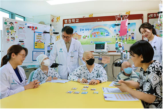 서울아산병원 어린이병원학교에서 김혜리 어린이병원학교장, 임호준 어린이병원장(왼쪽 첫 번째, 세 번째)이 자원봉사자 이은정 교사에게 한문수업을 듣고있는 소아암 환아들을 격려하고 있다.