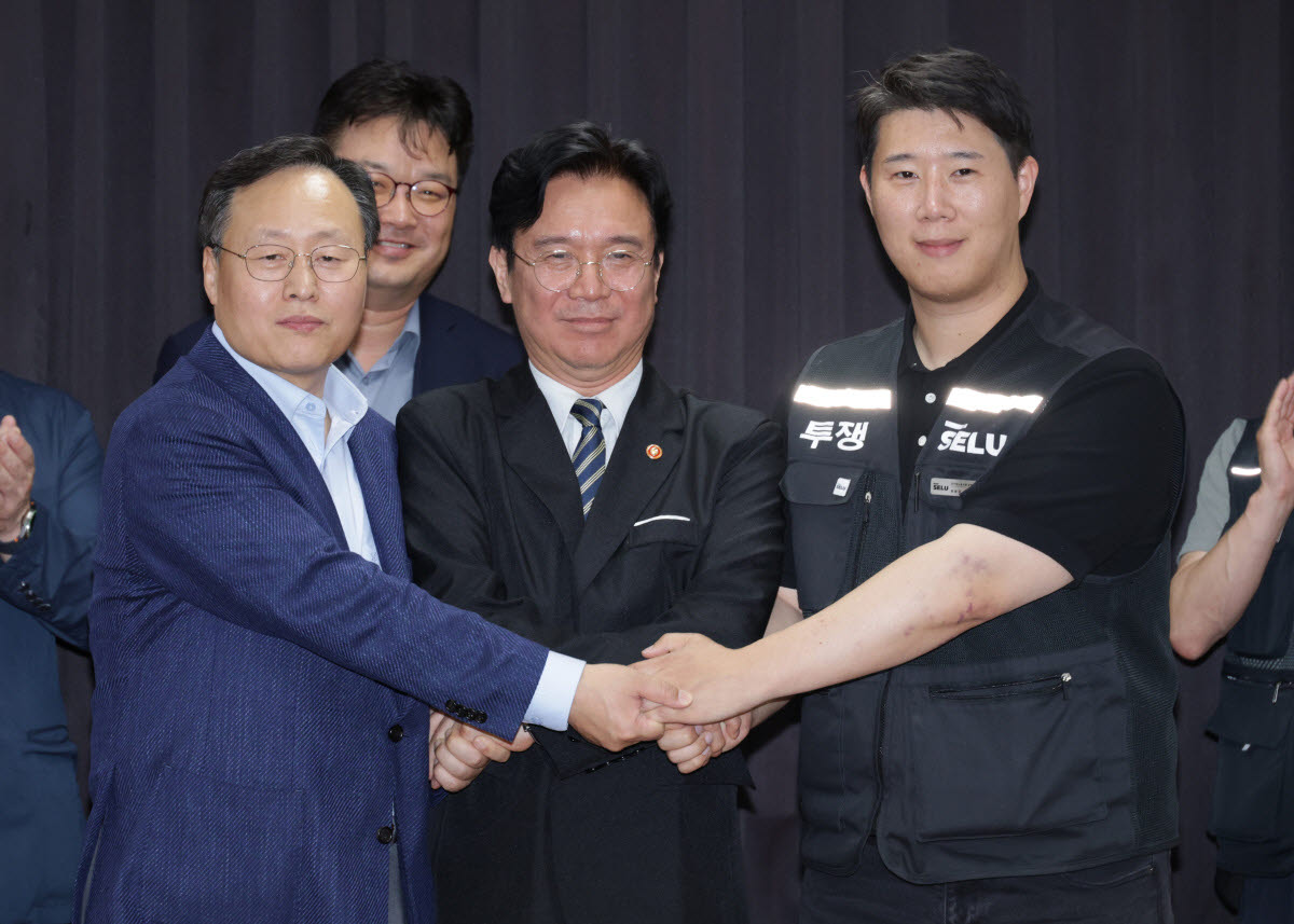 5월 20일 경기도 수원시 장안구 경기고용노동청에서 열린 삼성전자 임금협상을 마친 후 여명구 삼성전자 DS(디바이스솔루션·반도체 사업 담당) 피플팀장과 최승호 삼성그룹 초기업노동조합 삼성전자지부 위원장이 잠정 합의안에 서명한 후 김영훈 고용노동부 장관과 손을 맞잡고 있다. (사진=공동취재)