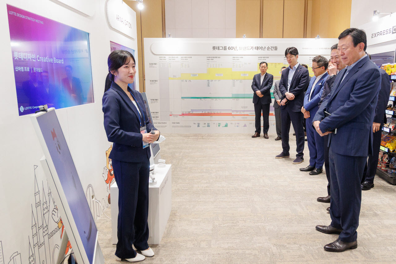 롯데는 10일 롯데월드타워에서 '2026 롯데 디자인전략회의'를 개최했다. 신동빈 롯데 회장(오른쪽 첫번째)이 젊은 디자이너들의 AI 프로젝트 결과물인 '로티로리 로봇 롯데월드 안내 서비스'에 대한 설명을 듣고 있다. (사진=롯데)
