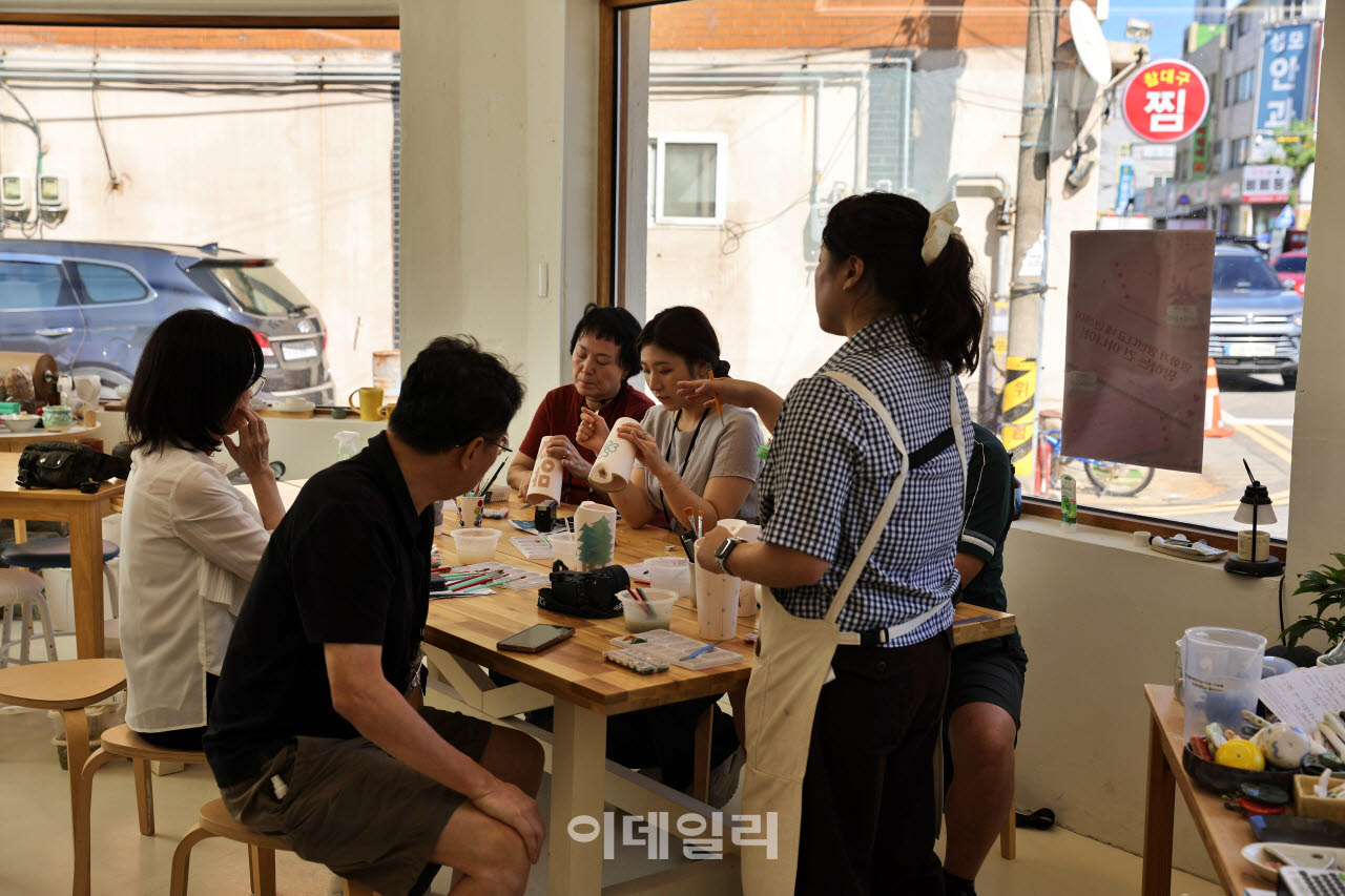 조치원의 유리공방 '오운'에서 참가자들이 도자기에 그림을 그리고 있다. 창밖으로 오래된 상점과 골목 풍경이 보인다.(사진=이데일리 강경록 여행전문기자)