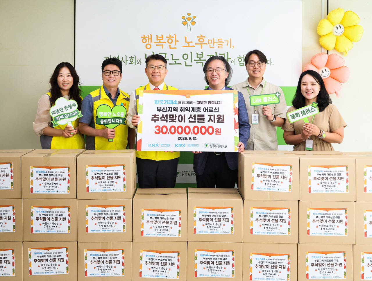 KRX국민행복재단 정상호 사무국장(전달보드 기준 왼쪽), 부산남구노인복지관 박시우 관장(전달보드 기준 오른쪽) 등 관계자들이 21일(월) 취약계층 어르신들을 위한 후원금 전달식 단체 기념촬영을 하고 있다. (사진=한국거래소)