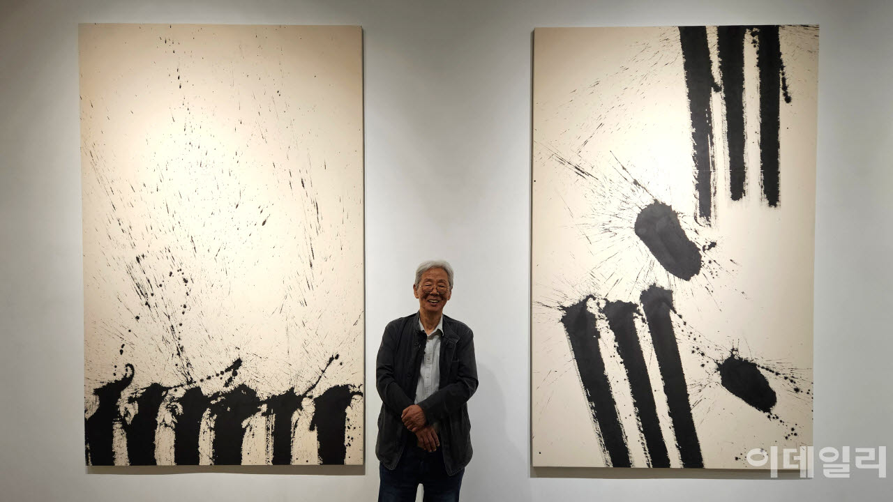 작가 김호득이 아트사이드갤러리 개인전 ‘-빼고 또 빼고-’에 건 자신의 작품 앞에 섰다. 왼쪽과 오른쪽 두 점 모두 ‘폭포’(2026, 250×157.7㎝)다(사진=오현주 문화전문기자).