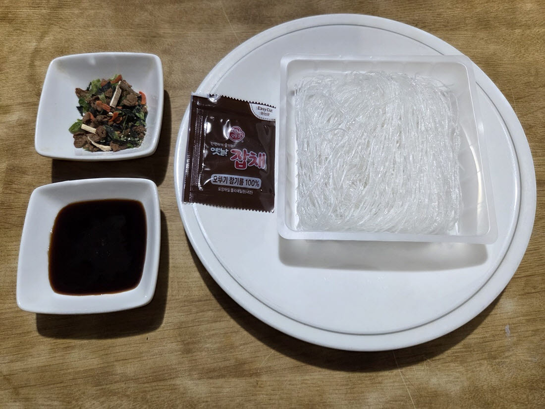 조리 전 오뚜기 ‘옛날잡채’의 당면과 건더기, 액체스프, 참기름. (사진=한전진 기자)