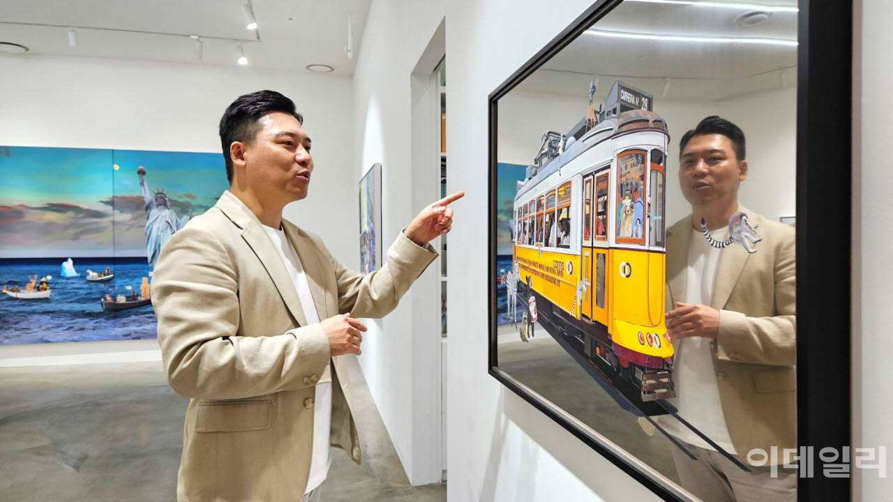 작가 정성준이 개인전 ‘다음 역은 내일입니다’에 건 한 점인 ‘행복이 멀리 있지 않아’(2026, 80×115㎝) 앞에서 작품 설명을 하고 있다. 전시작 중 유일하게 스테인리스스틸 판에 유화물감을 올려 제작했다(사진=오현주 문화전문기자).