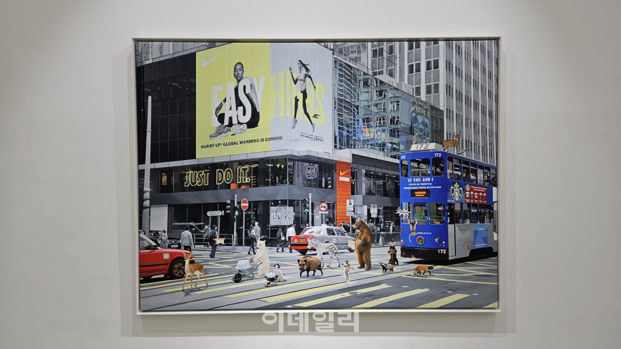 정성준의 ‘너도, 나도, 우리도 할 수 있어’(2026, 121.0×162.2㎝). 동물 친구들이 대도시 한복판 대로를 따라 시위행렬을 만들며 걷고 있다. 이들 뒤 건물 외벽에 나이키의 광고판이 보인다. 작품명에서 나이키의 메시지 ‘저스트 두 잇’을 연상할 수 있다(사진=오현주 문화전문기자).