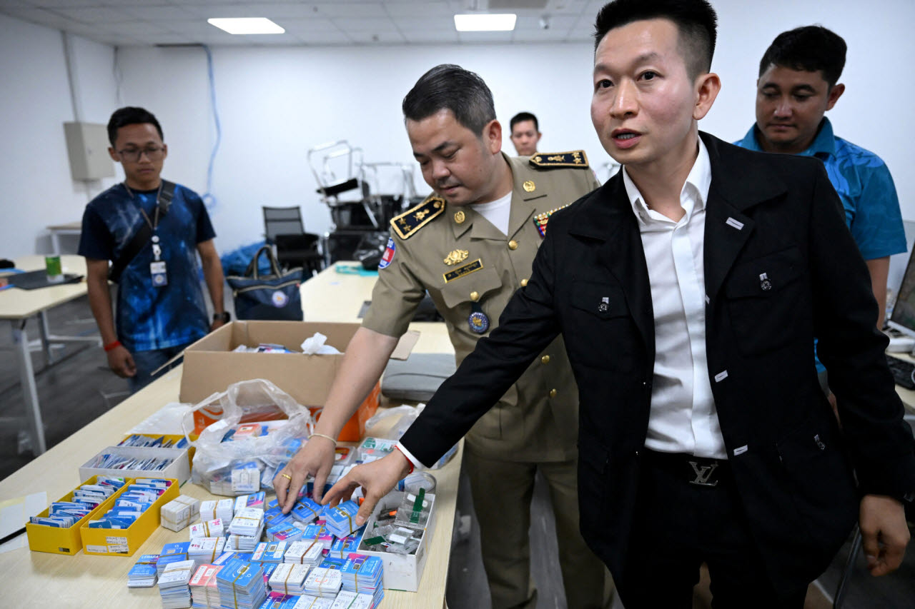 캄보디아 경찰과 검찰 관계자들이 지난 3월 11일 수도 프놈펜의 한 사이버 사기 거점을 급습해 압수한 외국 SIM 카드를 공개하고 있다. (사진=AFP)