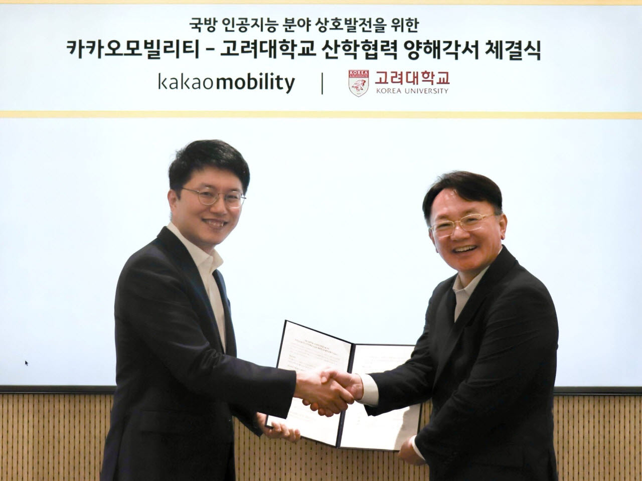 카카오모빌리티와 고려대학교의 ‘국방 인공지능(AI) 분야 상호발전을 위한 협력 양해각서(MOU)’ 체결식에서 류긍선(왼쪽) 카카오모빌리티 대표와 강석중 고려대학교 C5ISRT융합연구원장이 악수하고 있다.(사진=카카오모빌리티)