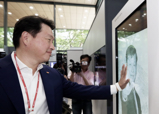 지난 2018년 8월 서울 종로구 서린동 SK사옥 1층 로비에서 열린 ‘고 최종현 회장 20주기 사진전’에서 아들 최태원 SK 회장이 아버지의 사진을 어루만지고 있다.(사진=SK그룹)