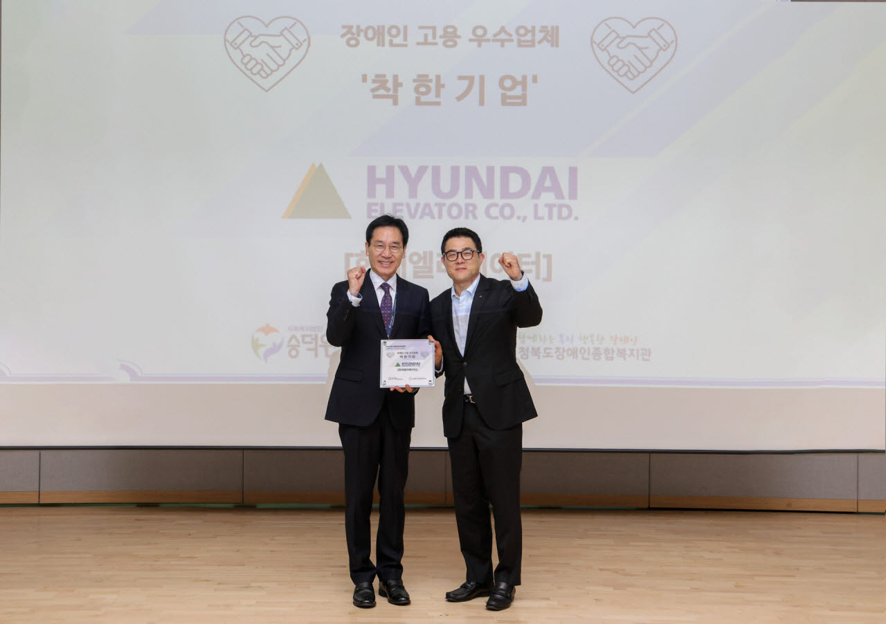 안지훈 현대엘리베이터 인사담당(오른쪽)과 이준호 사회복지법인 숭덕원 이사가 7일 충주 유네스코 국제무예센터에서 열린 ‘착한기업’ 현판 수여식을 마친 뒤 기념 촬영을 하고 있다. (사진=현대엘리베이터)