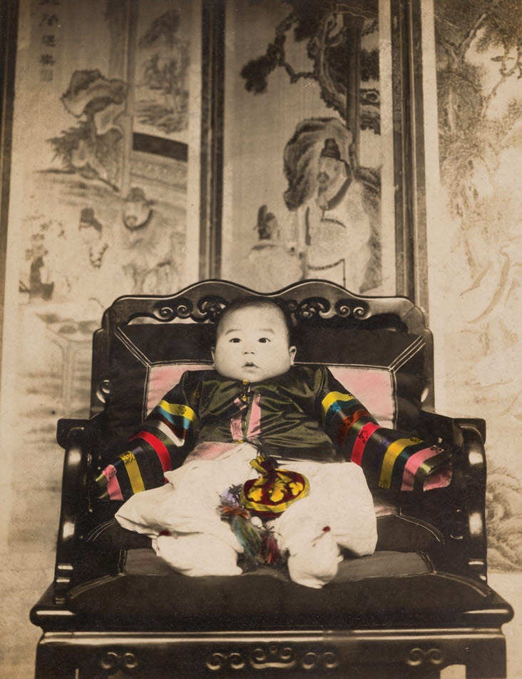 간송 전형필의 첫돌 사진(1907). 12폭 족자로 전해지는 ‘인물고실지도’가 본래 병풍이었다는 것을 확인한 결정적인 증거다. 사진의 뒷배경에 놓인 병풍 속 그림이 ‘인물고실지도’의 일부다(사진=간송미술문화재단).