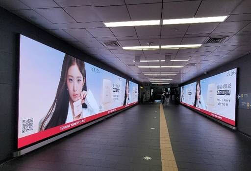 애경산업은 오는 30일까지 서울 강남과 홍대 등 주요 상권에서 스킨 퍼스트 메이크업 브랜드 에이지투웨니스의 대규모 옥외광고 캠페인을 진행한다. 서울 홍대입구역 공항철도 연결 구간에 설치된 디지털 전광판에 에이지투웨니스가 소개되고 있다. (이미지=애경산업)
