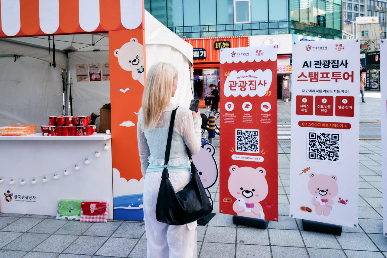 원시장을 찾은 한 외국인 관광객이 ‘AI 관광집사’ QR코드 안내판 앞에서 서비스를 살펴보고 있다. AI 관광집사는 길찾기와 점포 정보, 다국어 메뉴와 실시간 통역 기능을 제공한다.