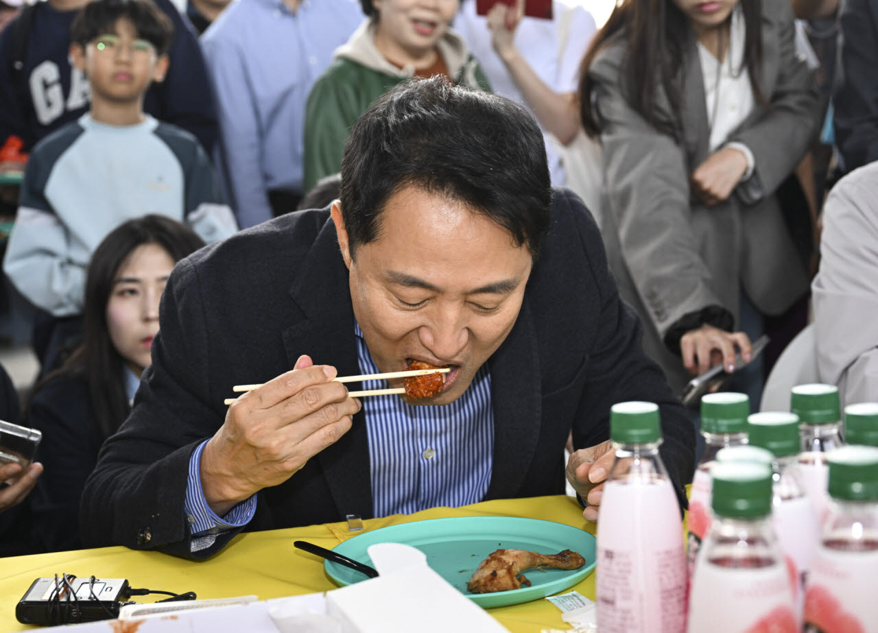 오세훈 서울시장이 25일 서울 서초구 잠수교 일대에서 잠수교 보행전용교 전환을 앞두고 현장 점검 도중 치킨데이 행사를 방문해 치킨을 먹고 있다.