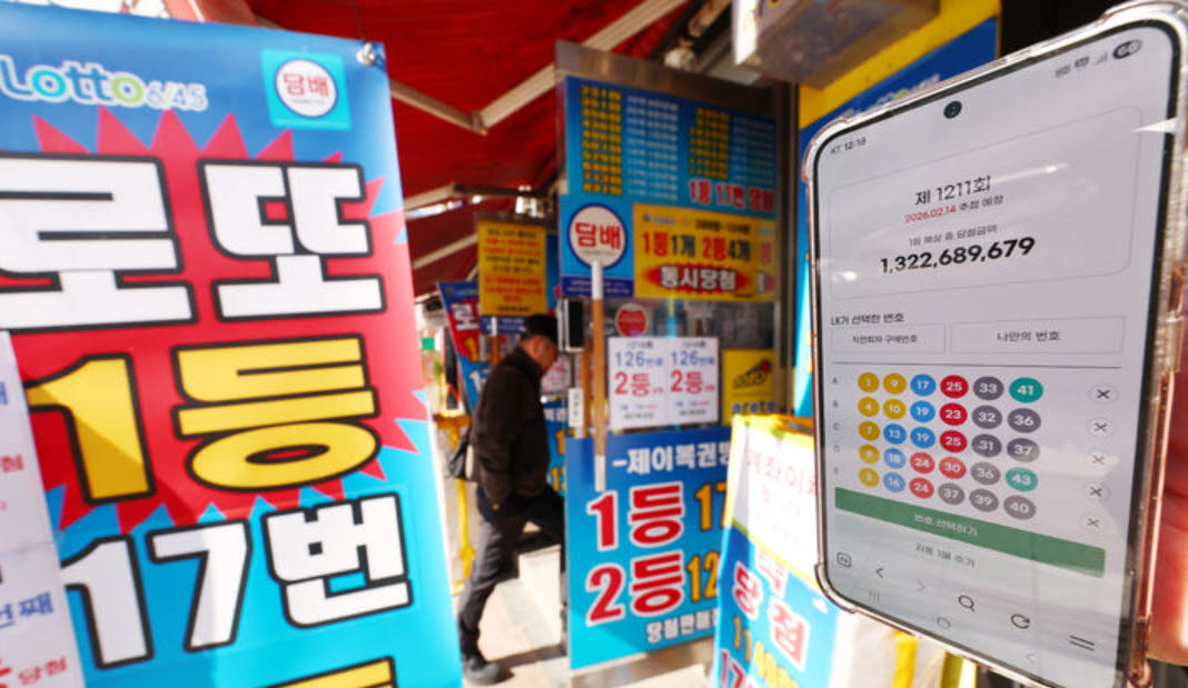 서울 시내 한 복권 판매점 앞에서 휴대폰 화면에 나오는 로또 모바일 판매 페이지 뒤로 시민들이 로또를 구매하고 있다. (사진=뉴시스)