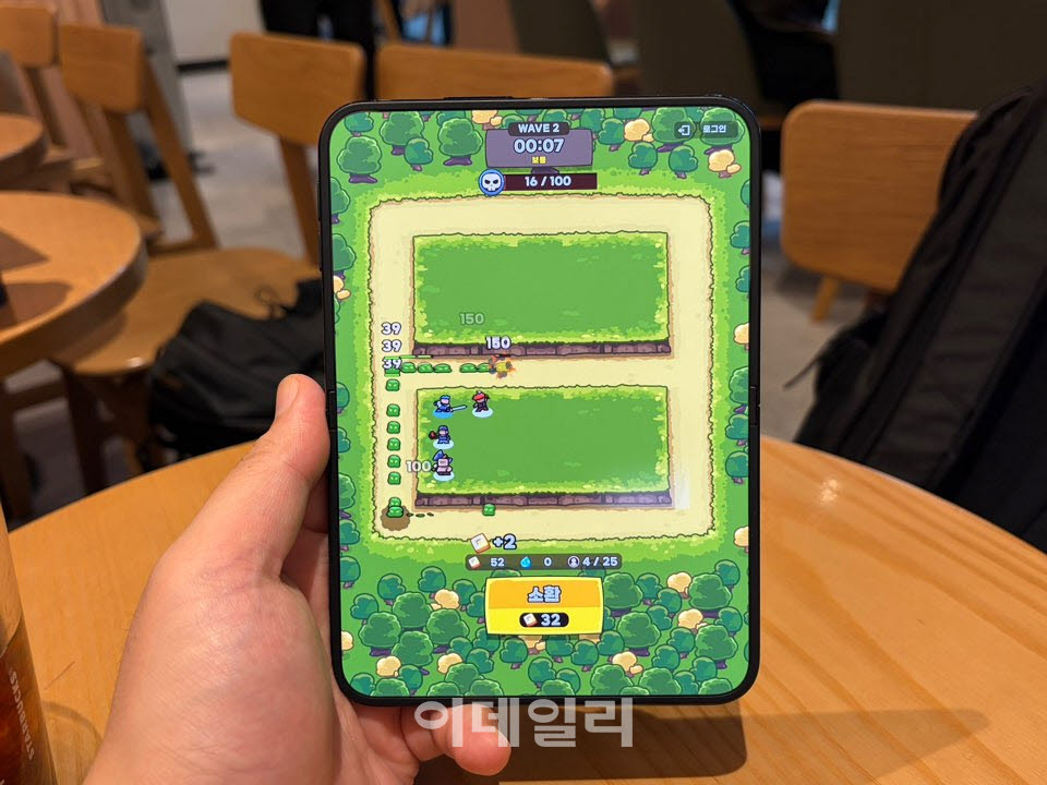 아이폰 듀오를 펼쳐 세로로 든 채 ‘운빨존많겜’을 실행한 모습. 게임 화면이 내부 디스플레이에 맞춰 넓게 표시된다. (사진=신영빈 기자)